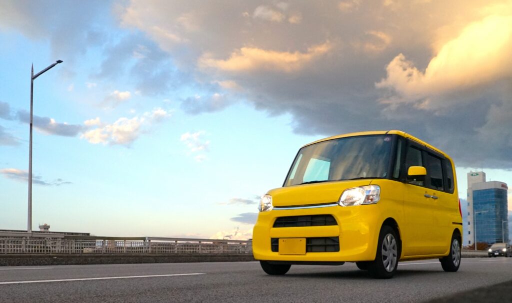 夕焼けを背景に止まる軽自動車